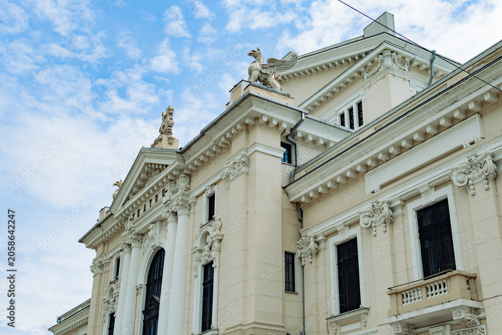 Obraz premium Classical theater building facade with statues and ornate architecture Description: Low angle architectural shot of an elegant national theater or opera house featuring classical columns, beautiful sc