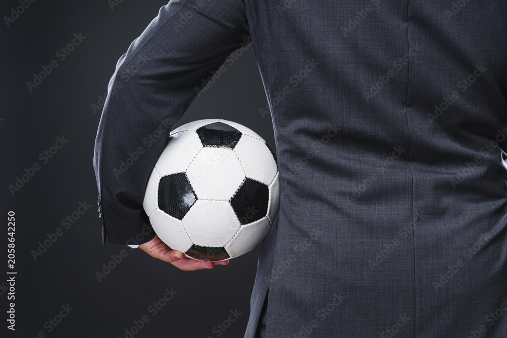 Naklejka premium a sporty man in an elegant suit with the soccer ball - coach or professional player concept