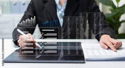 Fotografie Businesswoman reviewing performance reports and compliance checklist on digital dashboard, data analytics, financial auditing, project management, reporting accuracy, and corporate governance