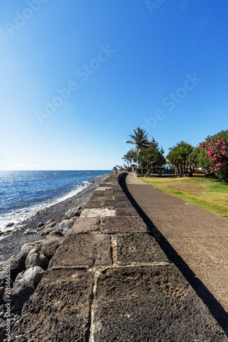 Stone seawall on sunny coastline Reunion Island