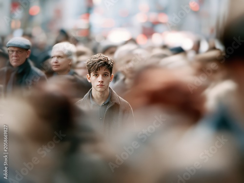 Young man standing motionless in crowded city street, urban solitude and focused expression