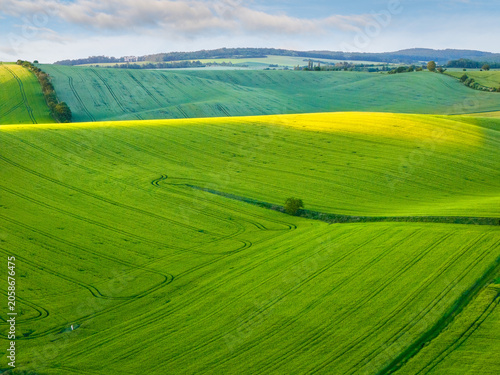 Aerial view of rolling green hills and vibrant yellow warm evening light just before sunset