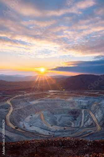 Majestic Sunrise Over a Vast Open-Pit Mine with Winding Roads and Dramatic Skies