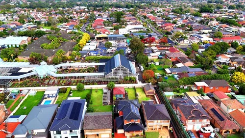 Drone panoramic aerial view of Sydney NSW Australia city Skyline and looking down on all suburban houses and streets of western Sydney of Burwood and Enfield