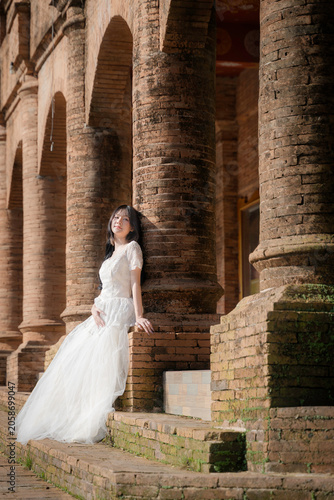 Portrait Fashion Asian Woman in White Gown at Ancient Brick Temple Architecture in Chiang Mai Thailand