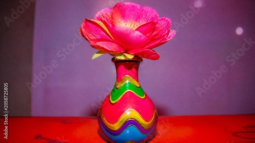 A cheap plastic flower in a garish vase, tacky aesthetic with bright colors.