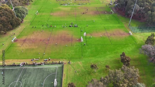 Children playing soccer with parents watching them in a western Sydney Park on a Sunday winter morning in Enfield Sydney NSW Australia