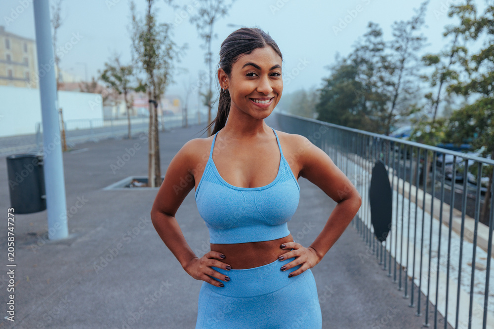 Naklejka premium Young woman smiling while exercising outdoors