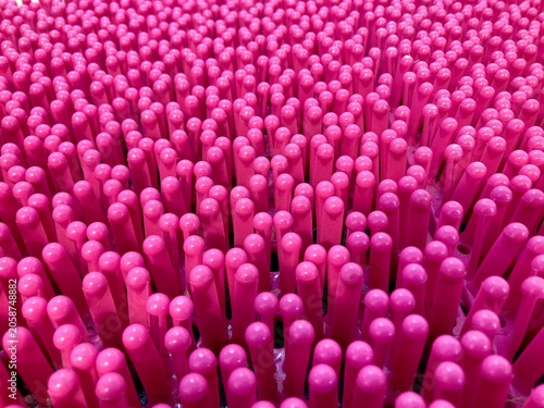 close up texture of a bright pink plastic brush with flexible round tipped bristles