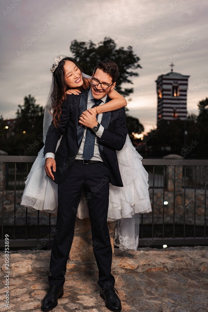 Fototapeta premium Happy mixed race wedding couple piggybacking outdoors