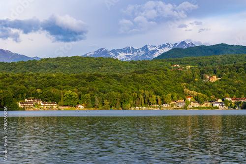 Villas on the opposite shore of the Lago Grande di Avigliana with the still snow-capped Alpine peaks in the background at sunrise in spring, Susa Valley