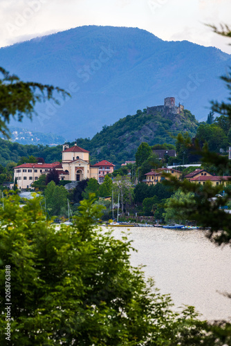 Village of Avigliana dominated by the ruins of its medieval castle at sunrise, seen from the opposite bank of the Lago Grande di Avigliana
