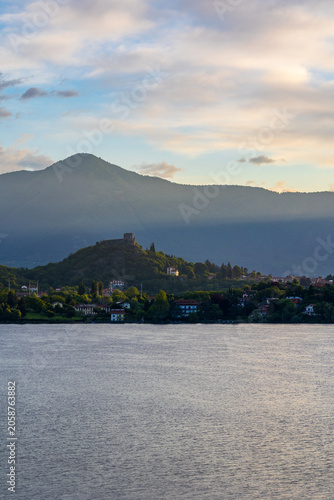 Village of Avigliana dominated by the ruins of its medieval castle at sunrise, seen from the opposite bank of the Lago Grande di Avigliana