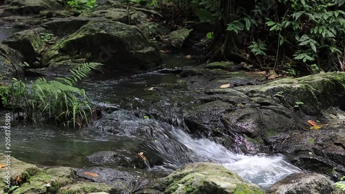 The video background features a natural landscape of a waterfall in a lush forest. Sam Lan Waterfall in Saraburi National Park boasts beautiful flowing water surrounded by diverse flora.