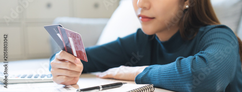 Business financial concept, stressed asian young business woman hand holding credit card for calculate accounting expense of bill, tax for payment on due deadline, trying to find money to pay debt.