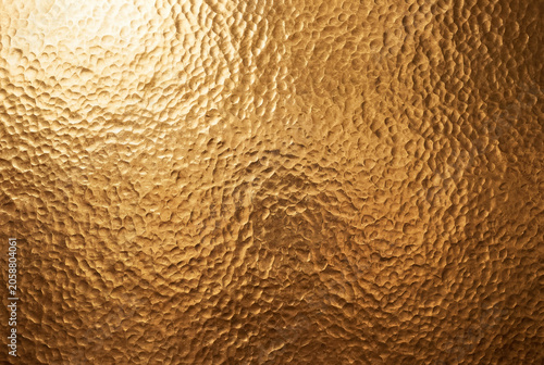 High angle close up textured surface of rich hammered deep gold background