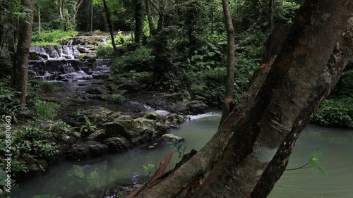The video background features a natural landscape of a waterfall in a lush forest. Sam Lan Waterfall in Saraburi National Park boasts beautiful flowing water surrounded by diverse flora.