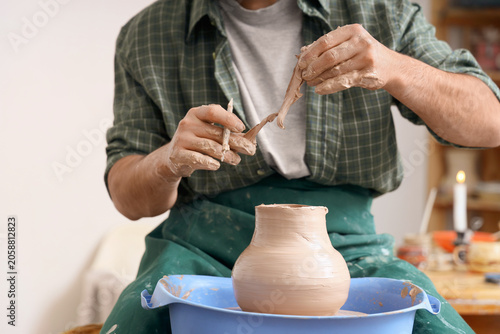 Potter shaping clay on pott...