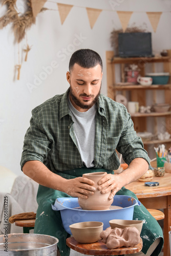 Focused male potter shaping...