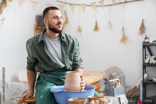 Young male potter working w...