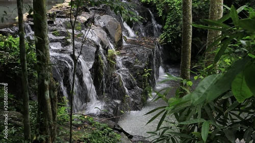The video background features a natural landscape of a waterfall in a lush forest. Sam Lan Waterfall in Saraburi National Park boasts beautiful flowing water surrounded by diverse flora.