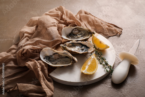 Fotografie Freshly shucked oysters with lemon wedges and thyme on marble board, seafood del