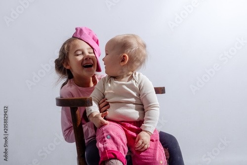 Billede på lærred Pretty little sisters are playing in the photo studio with white background