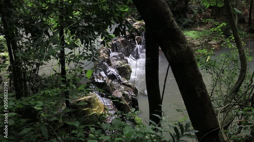 The video background features a natural landscape of a waterfall in a lush forest. Sam Lan Waterfall in Saraburi National Park boasts beautiful flowing water surrounded by diverse flora.