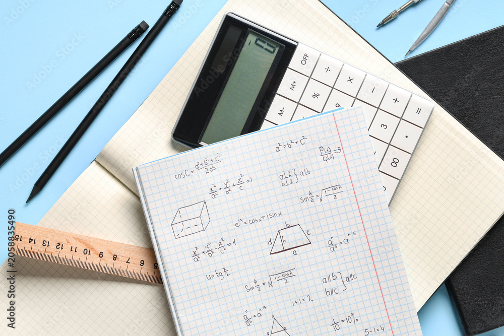 Naklejka premium Copybook with handwritten maths formulas and stationery on blue background