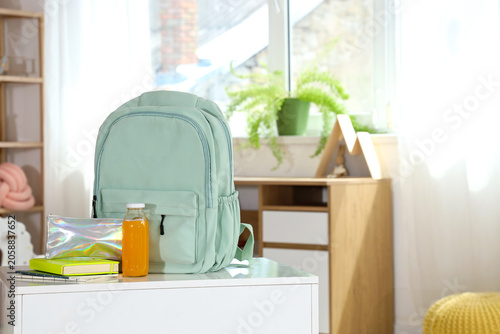 Backpack with pencil case and juice on table in childrens room