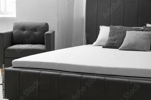 Foto New orthopedic mattress on stylish bed in room, closeup