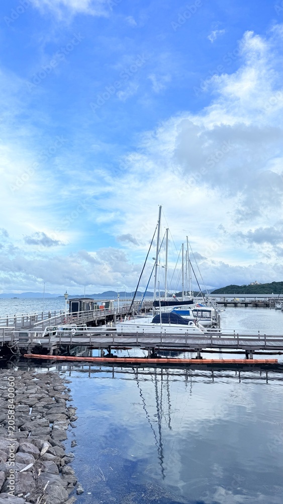 Fototapeta premium Calm harbor scene featuring rows of moored sailboats in Huis Ten Bosch, Japan