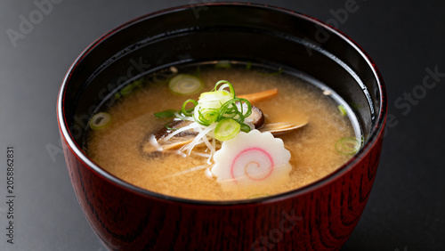 Traditional miso soup with vegetables and fish cake in wooden bowl  