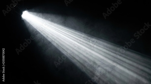 Bright light beam shining through dark smoke or fog effect