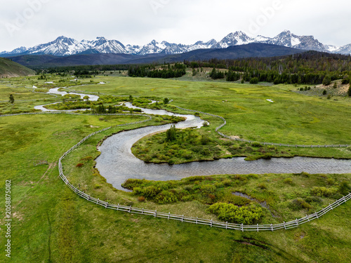 Aerial view of a meaning river with pole fence leading to mountains