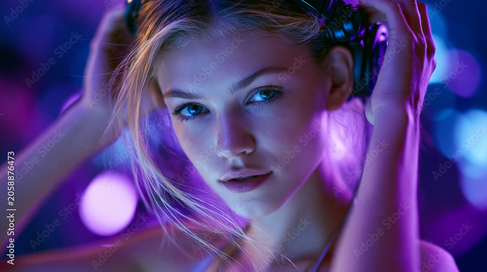 Fototapeta premium Lächelnde blonde Frau mit kurzem Haar unter blauviolettem Neonlicht