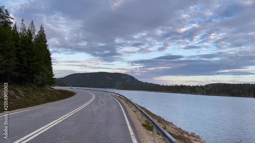 Driving on winding lakeside road through boreal forest in Lapland Finland