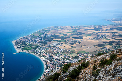Elevated high angle view of agricultural green fields adjacent to a deep blue sea
