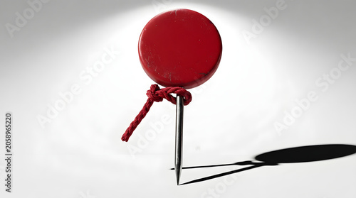 A vibrant red balloon, poised and ready for flight, casts a distinct shadow as it's secured by a simple knot and string. Its solitary presence evokes a sense of anticipation and whimsical charm.