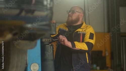 Caucasian male mechanic with glasses and a beard works alongside a female technician, reviewing a digital tablet and giving a thumbs-up. This high-energy commercial imagery represents gender diversity