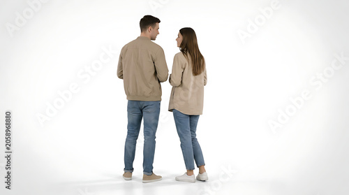 Full body shot of a young couple standing on a white background, looking at each other and talking, dressed in casual clothes.
