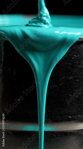Teal liquid flowing over dark textured surface in close up