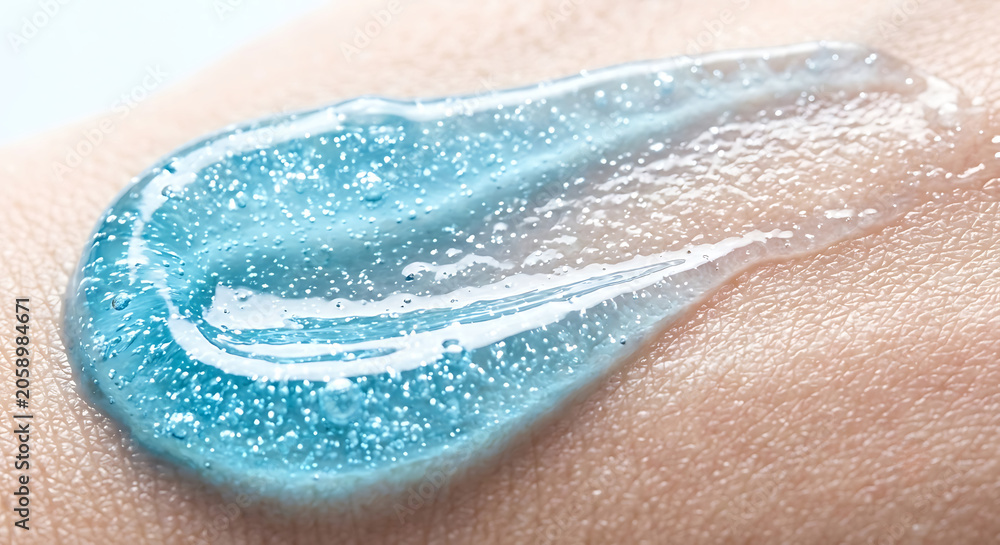 Fototapeta premium Light blue gel serum texture smeared on human skin surface macro close up for cooling hydration and fresh skincare product advertising.