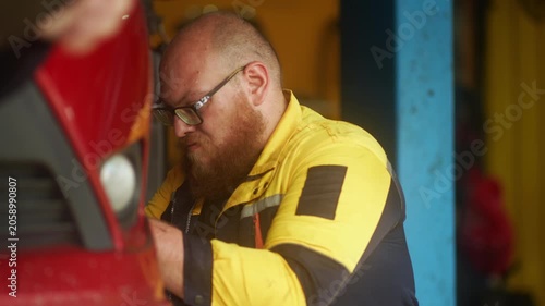 Caucasian male mechanic with glasses and a beard works alongside a female technician, reviewing a digital tablet and giving a thumbs-up. This high-energy commercial imagery represents gender diversity
