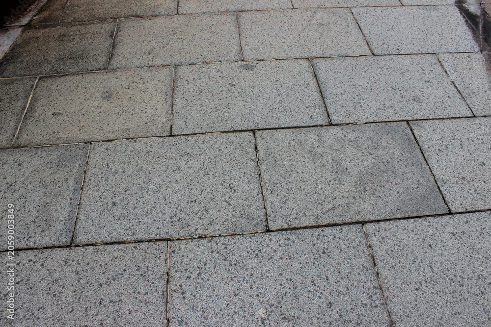 Fototapeta premium Gray granite outdoor walkway surface with consistent speckled stone tile texture.