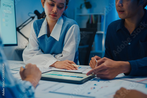 Close up asia businesspeople meeting plan analysis statistics brainstorm and tablet point graph chart employee take note in office conference room at night. Business finance partners strategy success.