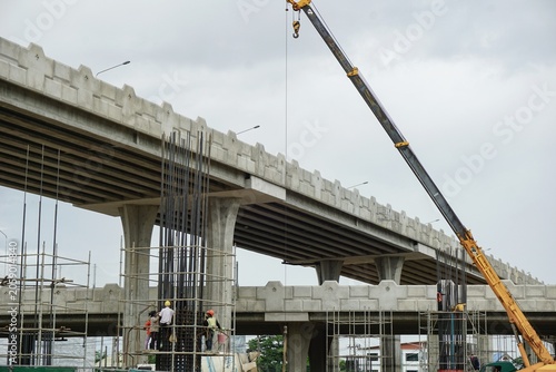 Active construction of a multi-level elevated road project with a crane and workers in Chiang Mai, Thailand on June 14, 2026.