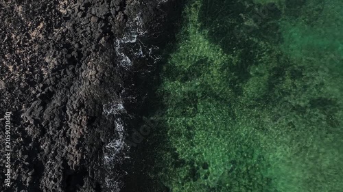 A drone flyover of a pebble beach where you can also see the sea
