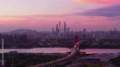 Sunset city skyline with bridge over river and evening traffic
