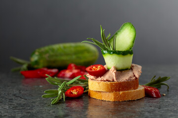 Bread slices with pate, cucumber, red pepper, and rosemary.